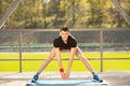 Young man training yoga outdoors. Sporty guy makes stretching exercise on a blue yoga mat, on the sports ground Royalty Free Stock Photo