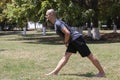 Young man training yoga outdoors. Sporty guy makes stretching exercise on a blue yoga mat, on the sports ground Royalty Free Stock Photo