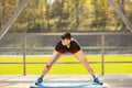 Young man training yoga outdoors. Sporty guy makes stretching exercise on a blue yoga mat, on the sports ground Royalty Free Stock Photo