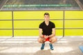 Young man training yoga outdoors. Sporty guy makes stretching exercise on a blue yoga mat, on the sports ground Royalty Free Stock Photo