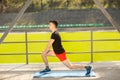Young man training yoga outdoors. Sporty guy makes stretching exercise on a blue yoga mat, on the sports ground Royalty Free Stock Photo