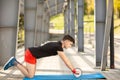 Young man training yoga outdoors. Sporty guy makes stretching exercise on a blue yoga mat, on the sports ground Royalty Free Stock Photo