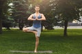 Young man training yoga in tree pose outdoors Royalty Free Stock Photo