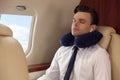 Young man with travel pillow resting while listening to music in airplane during flight Royalty Free Stock Photo