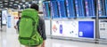 Young man traveler with backpack checking flight time, Asian passenger with hat looking to information board in international Royalty Free Stock Photo