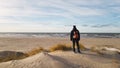 A young man traveler with a backpack stands on the beach and admires the view. Thinking about the future alone. Beautiful light,sa