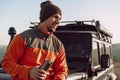 Young man traveler drinking from his thermocup while halt on a hike