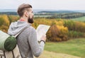 Young man traveler standing on top of the hill and looking to the map. Travel concept