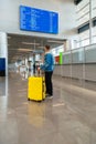 Young man traveler with suitcases at airport behind flight timetable. Man with bag and yellow suitcase luggage travel Royalty Free Stock Photo