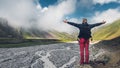 Young man traveler walking and enjoys view of summer spring mountains, rear view with copy-space. Concept of achieving motivation