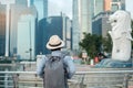 Young man traveling with backpack and hat in the morning, Solo Asian traveler visit in Singapore city downtown. landmark and
