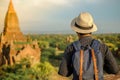 Young man traveling backpacker with hat, Asian traveler standing on Pagoda and looking Beautiful ancient temples, landmark and Royalty Free Stock Photo