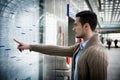 Young man traveling, reading train timetable in railway station Royalty Free Stock Photo