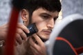 Young man trimming his beard in the mirror Royalty Free Stock Photo