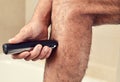 Young man trimming his legs with an electric trimmer Royalty Free Stock Photo