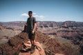 Young man trousist standing in front of Grand Canyon. Hiker with backpack enjoying view, USA. Travel and outdoort Royalty Free Stock Photo