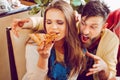 A young man is trying to pick up the last piece of pizza from a girl. Greed.