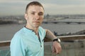 A young man in a turquoise shirt, short sleeve, portrait against the background of a European city. One person, a male, short hair