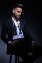 Young man in tuxedo sitting with hand in pocket