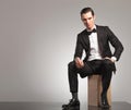 Young man in tuxedo is sitting with open coat