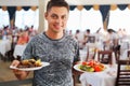 Young man with two dishes in hands at restaurant Royalty Free Stock Photo
