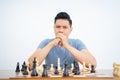 Young man with two hands in mouth while playing chess Royalty Free Stock Photo