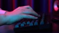 A young man is typing on a computer keyboard. Hands close up. Blue and red light falls on the hands. Royalty Free Stock Photo