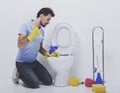 Young man unclogging toilet with plunger.