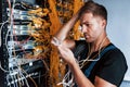 Young man in uniform feels confused and looking for a solution with internet equipment and wires in server room