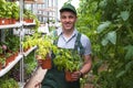 A young man in uniform works in a greenhouse.