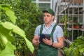 A young man in uniform works in a greenhouse.