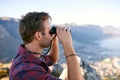 Young man using binoculars on a moutain side Royalty Free Stock Photo