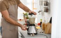 Young man using blender to cook cream soup in kitchen Royalty Free Stock Photo