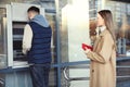 Young man using cash machine for money withdrawal outdoors. ATM queue Royalty Free Stock Photo