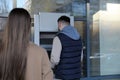 Young man using cash machine for money withdrawal outdoors. ATM queue Royalty Free Stock Photo