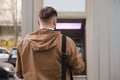 Young man using cash machine for money withdrawal outdoors, back view Royalty Free Stock Photo