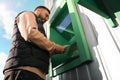 Young man using cash machine for money withdrawal outdoors, low angle view Royalty Free Stock Photo