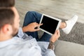 Young man using digital tablet with blank black screen, browsing website or showing new app, sitting on sofa at home Royalty Free Stock Photo