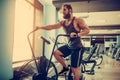 Young man using exercise bike at the gym. Fitness male using air bike for cardio workout at crossfit gym.