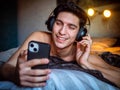 Young Man Using Headphones Lying Alone On His Bed Royalty Free Stock Photo