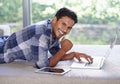 Connected to the world wide web. A young man using his laptop with his digital tablet lying next to him. Royalty Free Stock Photo