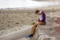 Young man using his mobile phone on the beach.