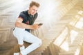 Young man using his smartphone with headphones, listen the music and sit on the floor Royalty Free Stock Photo