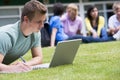 Young man using laptop on campus lawn Royalty Free Stock Photo