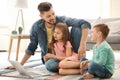 Young man using laptop with children at home