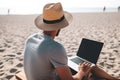 Young man using laptop computer on a beach. Freelance work concept