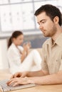 Young man using laptop at home woman in background Royalty Free Stock Photo