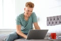 Young man using laptop while sitting on bed Royalty Free Stock Photo