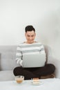 Young man using latop when sitting on sofa