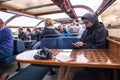 Young man using a mobile phone on interior seating inside a glass roofed sightseeing canal cruise trip boat for tourists